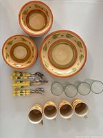three ceramic bowls, four mugs, four tumblers, flatware bundles