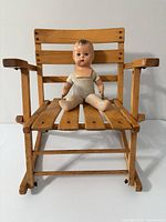 Front view of child’s wooden rocking chair with doll seated