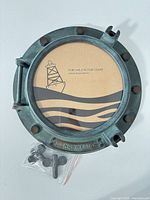 Front view of verdigris metal porthole frame with cardboard photo insert and mounting hardware bag