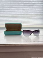 Sunglasses and open Tiffany blue hard case displayed on windowsill