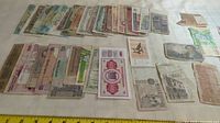 List of 40 assorted bank notes laid out on a table showing variety in size, color, and condition.