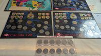 Five Canada 125 coin sets by province displayed flat, showing the coin placements and packaging.