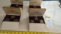 Four open boxes showing bronze plaques and stamps, each set in separate compartmented box with embossed lid.