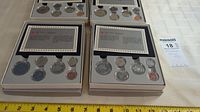 Overview of two of the four 1986 Royal Canadian Mint specimen sets showing five coins in protective capsules within white presentation boxes and informational cards.