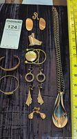 Full view of assorted vintage copper jewelry pieces spread out on a dark velvety surface including earrings, pendants, chains, and bracelets