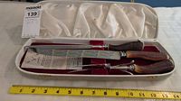 Full view of the vintage carving set in its lined presentation case showing the knife, fork, and sharpening steel with wood handles.