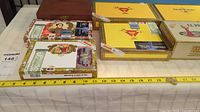 Top-down photo showing seven cigar boxes aligned with measuring tape for size reference, including Romeo y Julieta and yellow N.A. Premium boxes