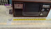 Front view of vintage Sears entertainment unit showing the radio, clock, and TV screen with a yellow measuring tape in front.