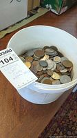 Top view of plastic bucket filled with assorted coins and tag