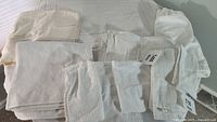 Lot of 10 white towels of various sizes and textures laid out on a flat surface.