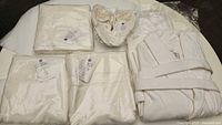 Top-down photo showing all set items individually arranged: bathrobe, towel, bath mats, slippers in white cotton.