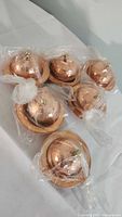 6 small copper finish Turkish-style serving dishes with lids and base plates, wrapped in plastic for protection.