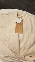 Close up of white soft terry cloth robe with attached care and origin tag, showing well-maintained fabric texture and size label S/M