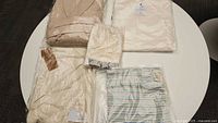 Top down photo showing all items in set on white table, including robe, towels, cover-up, and mitts in packaging.