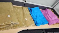 Two unopened packs and loose sheets of gold non-woven tissue paper, along with blue and pink tissue paper sheets.