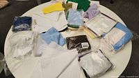 Overview of assorted washcloths and cleaning cloths on a round white table, including some packaged and loose cloths in various colors.