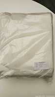 Cream satin duvet cover in original packaging with label showing brand, thread count, and dimensions.