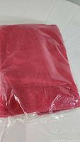 Folded red towel inside a clear plastic bag, showing towel texture and folded edges.