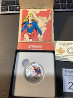 Single 2015 fine silver coin in capsule, displayed in white case with colorful Supergirl comic artwork and Certificate of Authenticity visible.