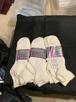 Nine pairs of white Spalding athletic socks arranged in three bundles of three pairs each on a black cloth background.