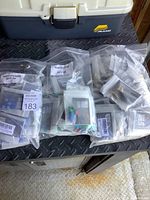 Plastic bags containing sets of bicycle valve caps and adaptors in original Bike Bits packaging placed on a black metal surface near a toolbox.