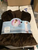 Photo showing brown fleece robe folded and secured with a paper band showing model images and labeled size.