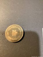 Close-up photo showing the coin on a dark surface, revealing the obverse side with the Confederate star emblem and the text 'CANADA CONFEDERATION 1867-1967'. Minor surface marks visible but overall good condition.