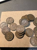 Coins spread in two piles on brown paper showing both sides with George VI and maple leaf designs. Visible dates include 1947 and 1941.