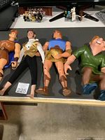 Four vintage Disney action figures laid out on a flat surface. Figures include Hercules, Prince Charming, another Hercules, and Quasimodo.