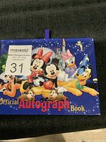Front cover of the official Disney autograph book featuring several iconic Disney characters and castle background.