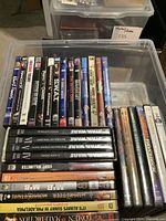 Clear photo showing a bin of DVDs with visible titles including Star Wars box sets, S.W.A.T., Paycheck, and others.