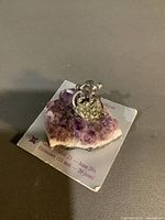 Raw amethyst cluster with attached small metal Gemini zodiac figure on original bilingual info card.
