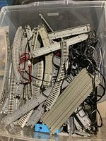 Top view of large plastic container filled with mixed straight, curved, and switch Kato N scale model train tracks with electrical wires and connectors for controllers and switches.
