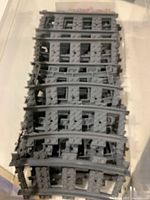 Stack of multiple dark gray curved LEGO train track pieces, showing top and sides with studs and track connectors.