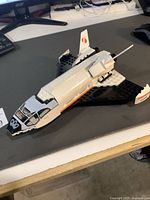 Front side view of the pre-built LEGO Space Shuttle showing the cockpit, white and black body with orange accents.