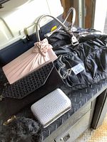 Photo showing 5 ladies handbags, clutches, and purses arranged on a black surface, highlighting different styles and materials.