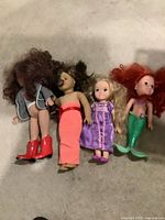 Four medium-sized dolls including mermaid and princess styles, showing outfits and sizes.