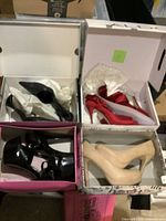 Four pairs of women's high heel shoes in their original boxes, showing variety in color and style including black, red, and beige tones.