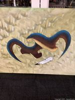 Full view of the watercolor painting showing a large stylized bird with human face, flying over a smaller bird and a feather on an earth-toned background.