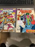 Photo of two Marvel Comics issues from 1989-1990, Avengers West Coast and Iron Man, placed side by side on a surface with a keyboard in the background.
