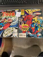 Photo of two comic books laid side-by-side, The Mighty Thor Annual on left and Excalibur Annual on right, both bagged with sticker labels.