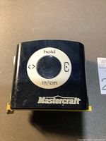 Front view of Mastercraft digital tape measure showing the control buttons and brand name.
