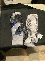 Both scarves folded and partially rolled on a black surface, showing their pattern and size.