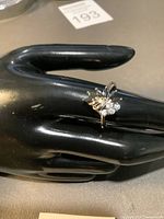 Silver 925 floral cluster ring on black display hand, showing side and angle views of the ring and cluster of cubic zirconia stones.