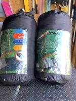 Two Sportek sleeping bags inside black storage bags with product labels visible.