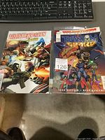 Two comic books laid flat on floor with keyboard in background. One is Thunderbolts vs Avengers 150th issue by Marvel, the other Phantom Guard #1 by Wildstorm, both bagged for protection.