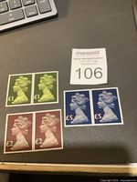 Six UK postage stamps displayed on a gray surface, including two £1 green, two £2 brownish-red, and two £5 dark blue Machin series stamps featuring Queen Elizabeth II profile.