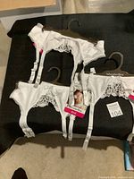 Three white WonderBra garter belts hanging on hangers, showing lace and strap details, new with tags.