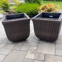 Both outdoor planters together on patio surface surrounded by greenery. Showcases size and style for outdoor use.