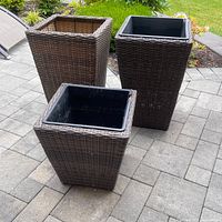 Three square outdoor planters with brown synthetic wicker exterior and black liners shown outdoors on patio.